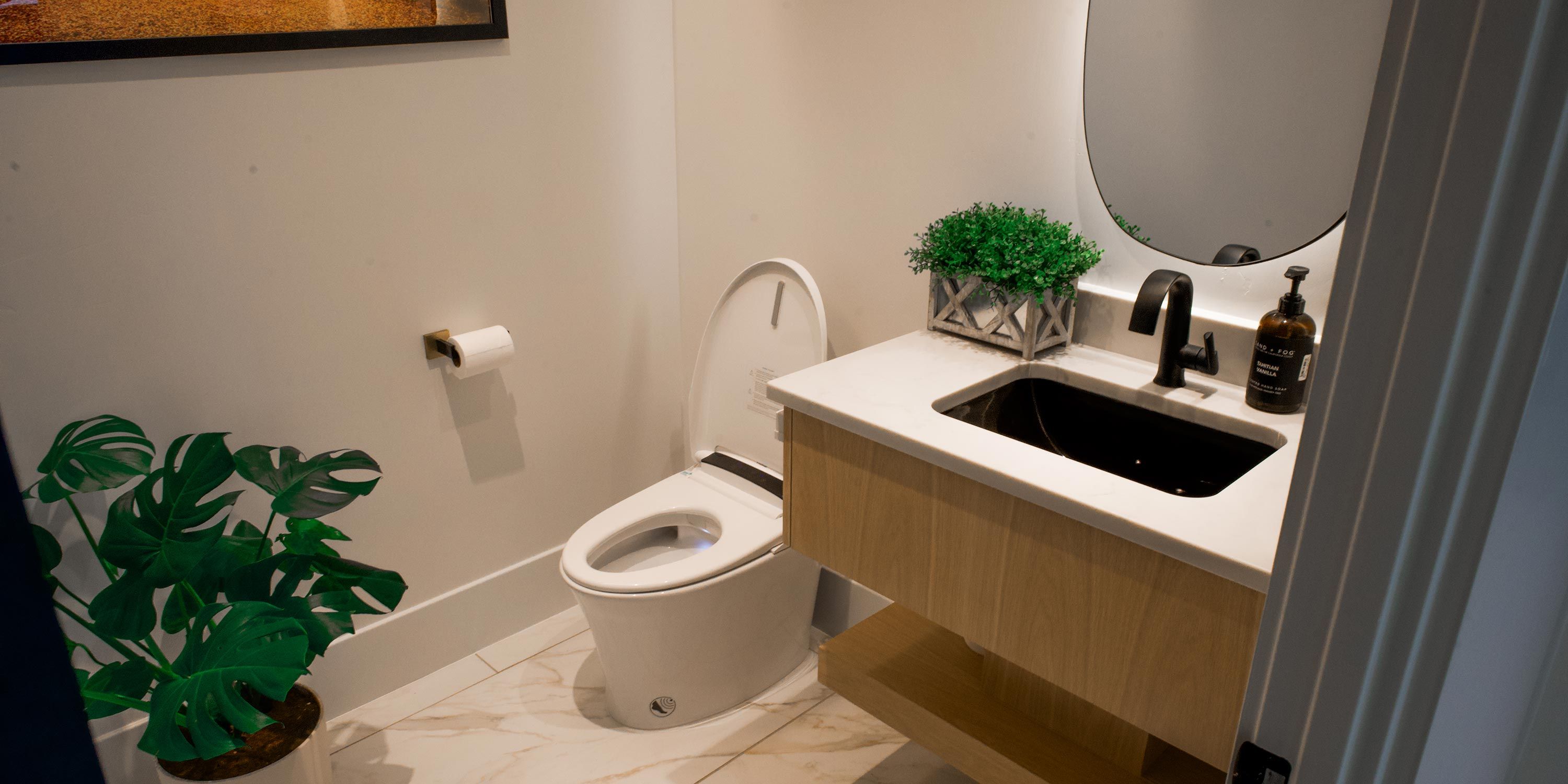 A sleek and modern bathroom with a smart toilet and stylish sink, featuring Control4 smart home technology.