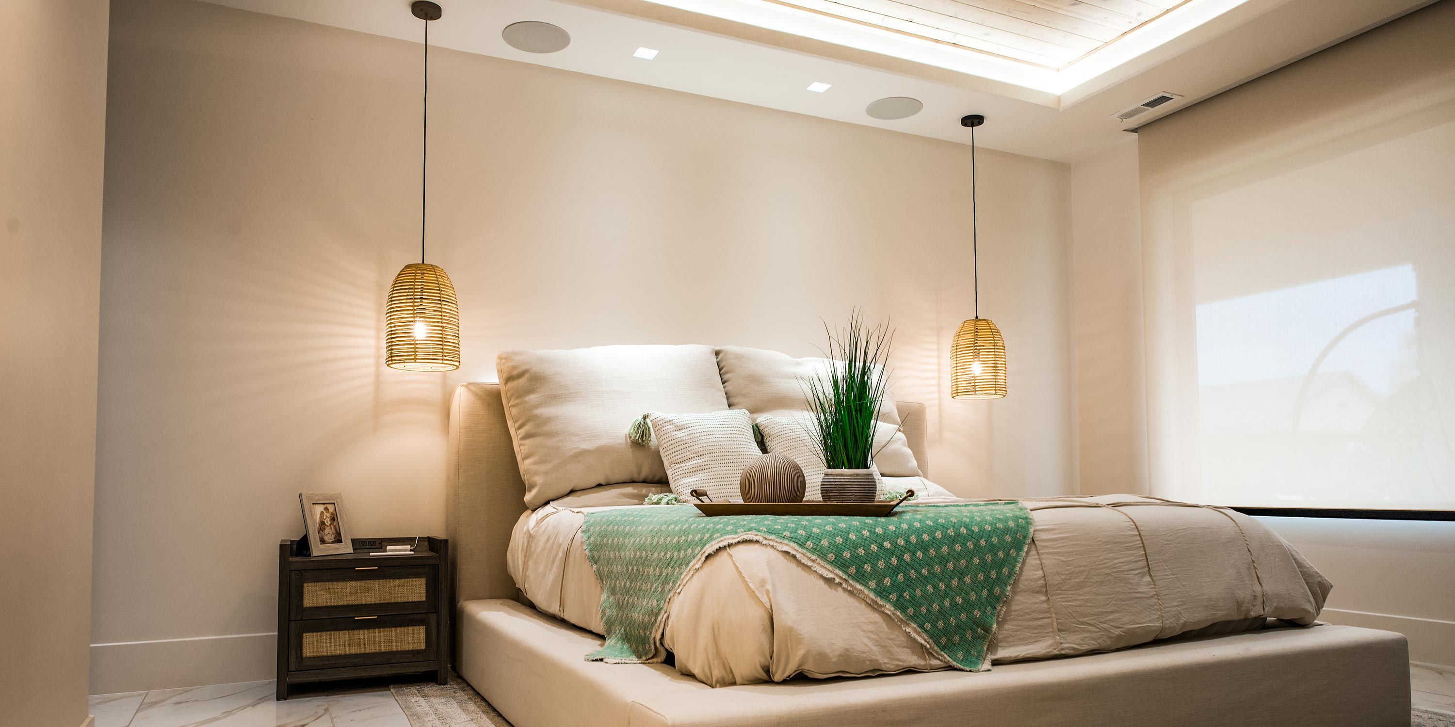 A cozy master bedroom with pendant lights and a comfortable bed, equipped with Sonance speakers for a high-quality audio experience.