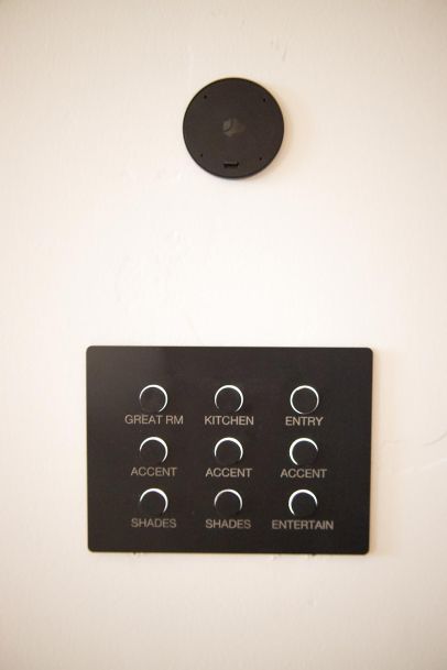 A Lutron Alisse smart home control panel with buttons labeled for areas including Great Room, Kitchen, Entry, Accent, and Shades, with a black Josh AI Nano is above it