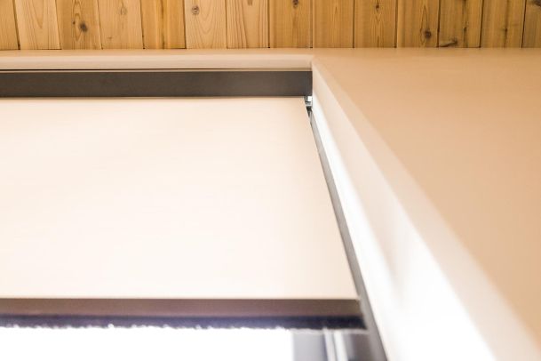 Close-up view of a modern window shade with a wooden valance.