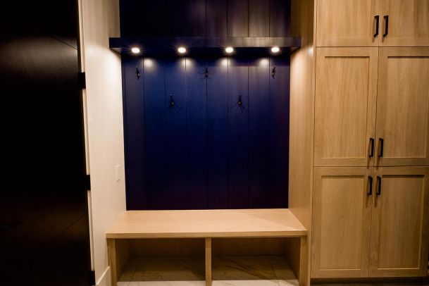 Mudroom with dark blue accents, wooden bench, and ample storage.