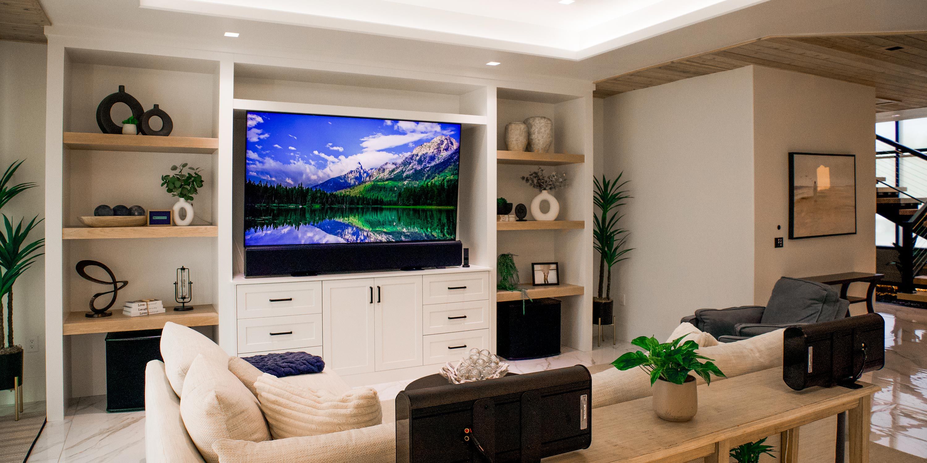 A luxurious great room with a large TV and stylish decor, controlled by Lutron lighting system.