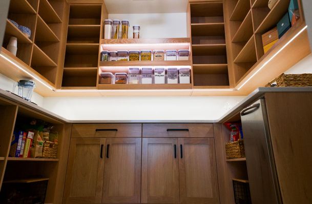 Pantry with organized shelving, containers, and under-cabinet lighting.