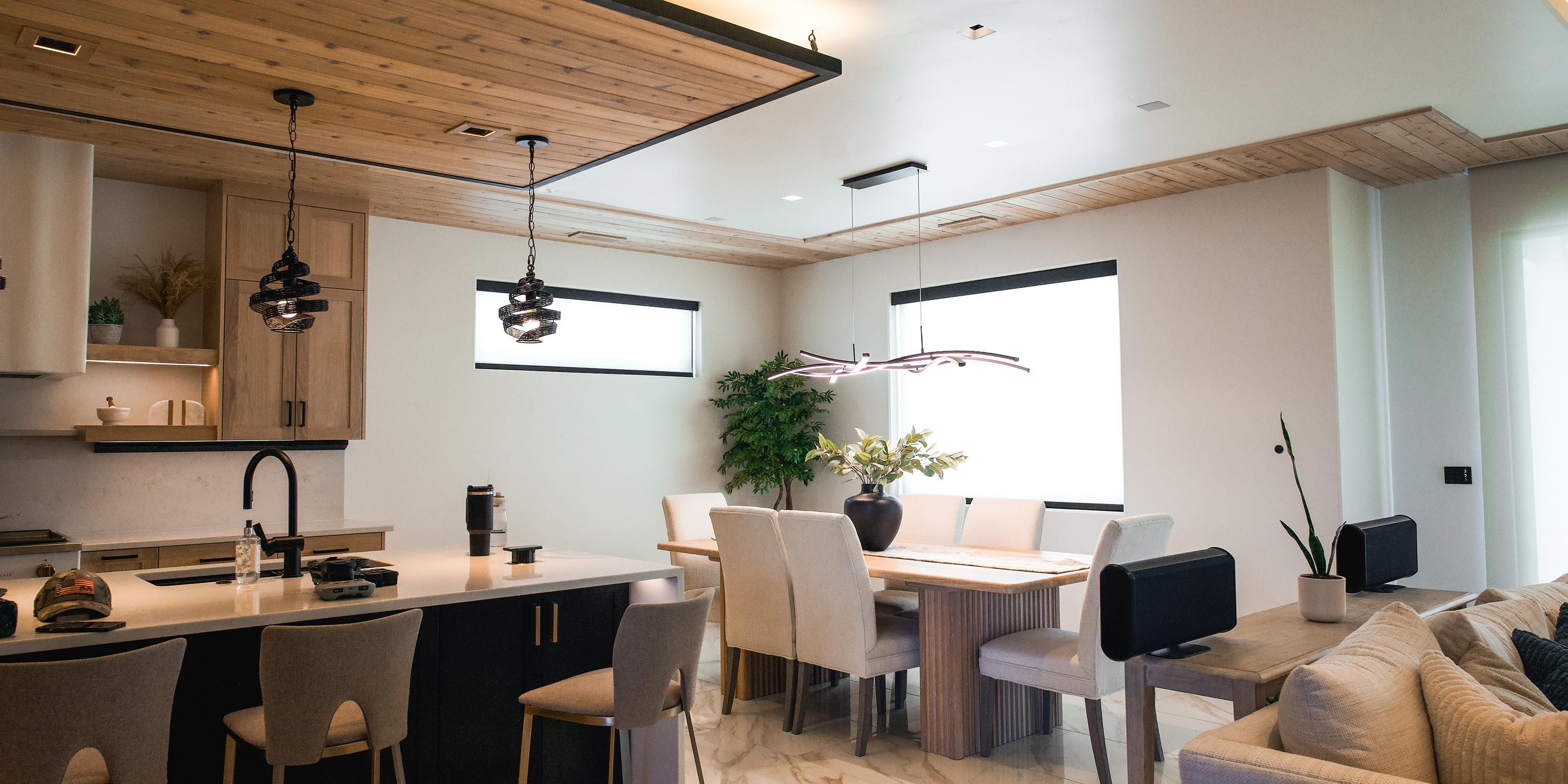 A modern kitchen and dining room with elegant lighting and comfortable seating, integrated with Savant home automation system.