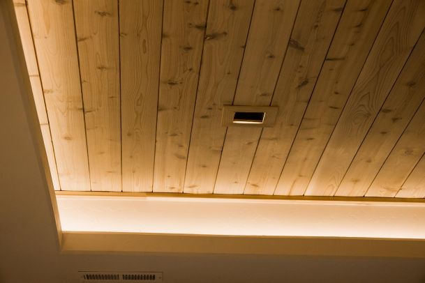 Wooden ceiling with recessed lighting and a subtle indirect lighting strip.