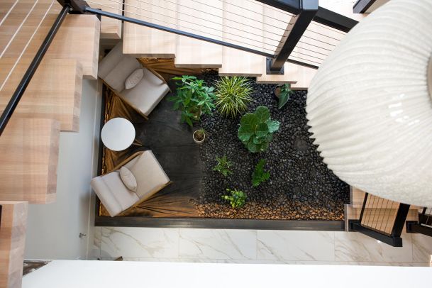 A view from above of a modern staircase with a small indoor garden area and seating.